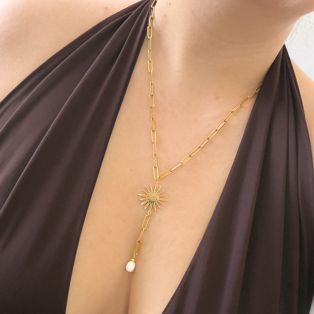 Goldene Solara Y-Kette mit Sonne und Perle am Dekolleté getragen