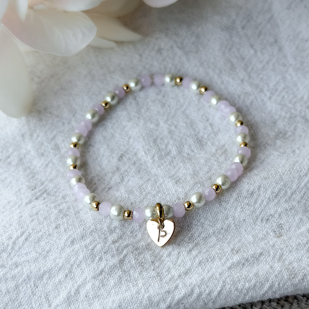 Personalisiertes Perlenarmband mit Herz-Anhänger, rosafarbenen Glasperlen, weißen Muschelperlen und 18k vergoldeten Zwischenperlen.