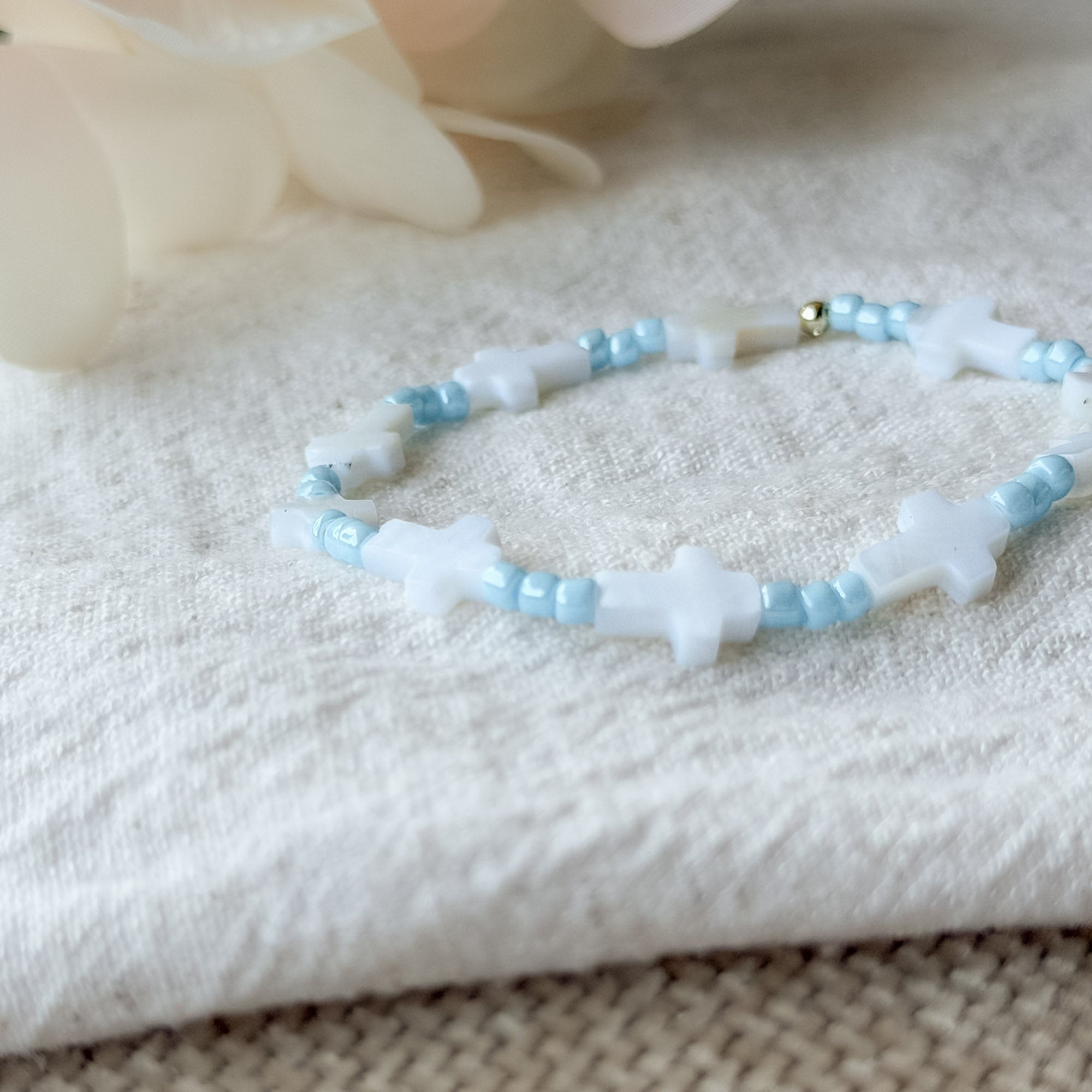 Detailaufnahme des Noa Armbands mit weißen Muschelkreuzen und hellblauen Miyuki-Perlen