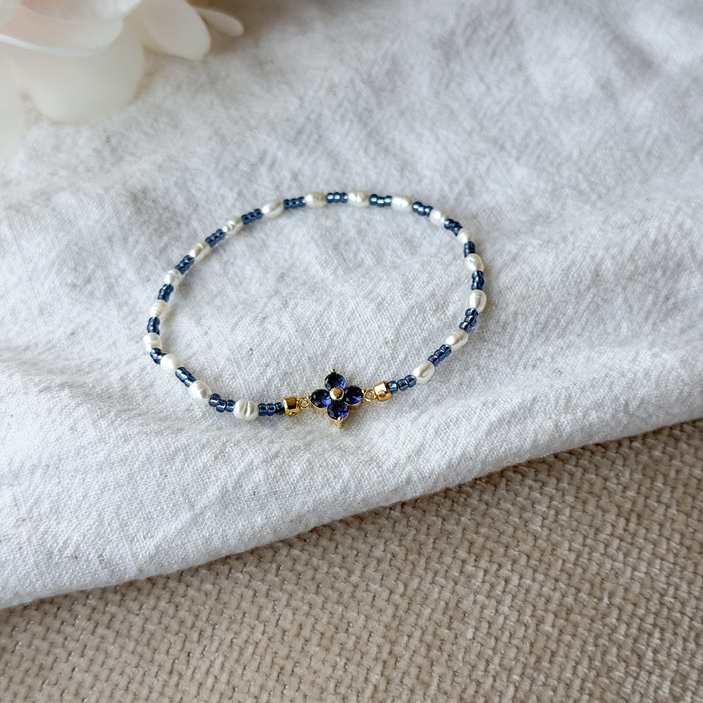 Elegantes Perlenarmband mit weißen Süßwasserperlen, blauen Miyuki-Perlen und einer funkelnden Zirkonia-Blüte