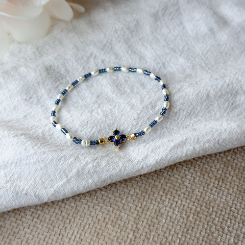 Elegantes Perlenarmband mit weißen Süßwasserperlen, blauen Miyuki-Perlen und einer funkelnden Zirkonia-Blüte
