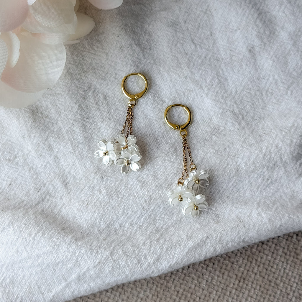 Romantische Edelstahl-Ohrringe mit Perlmutt-Blüten und vergoldeten Huggie-Creolen – leicht und elegant.