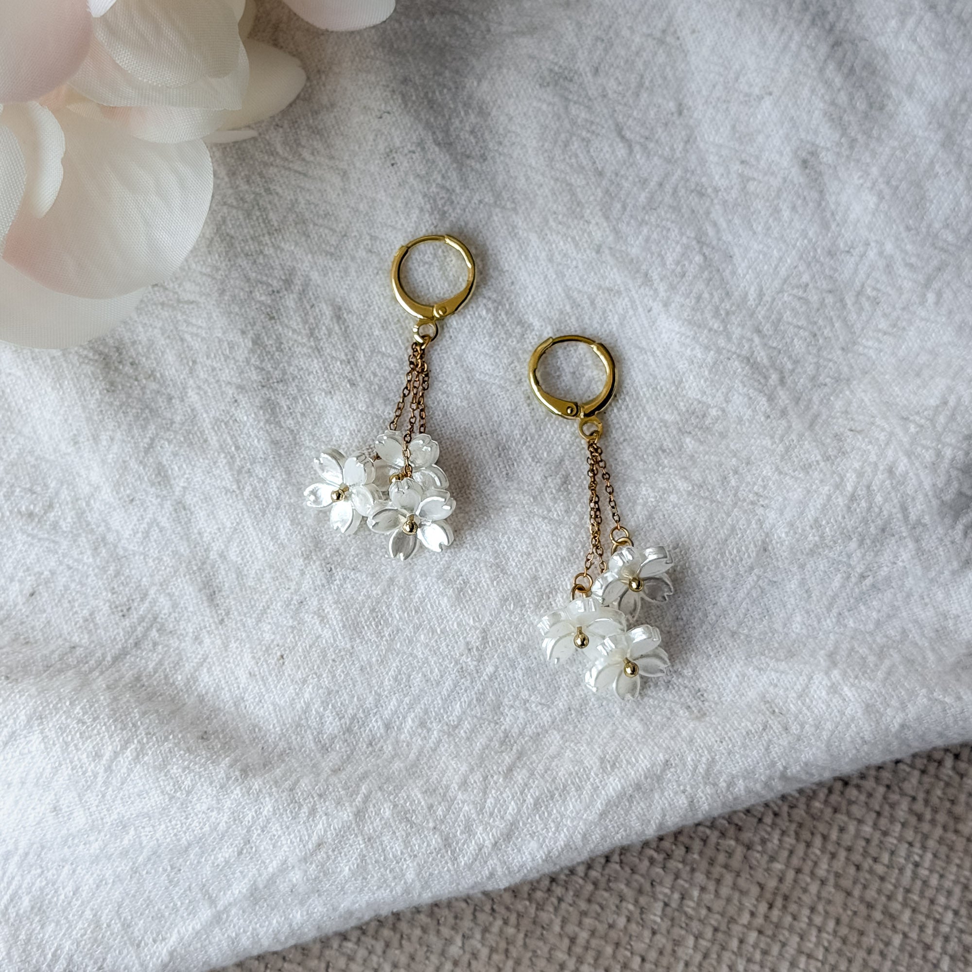 Romantische Edelstahl-Ohrringe mit Perlmutt-Blüten und vergoldeten Huggie-Creolen – leicht und elegant.